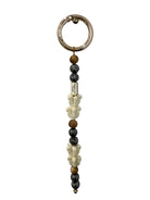 single lei keychain featuring white crown flower, wood and lava beads with a small gold bar showing our oceans end logo and a gold attachment hoop on top